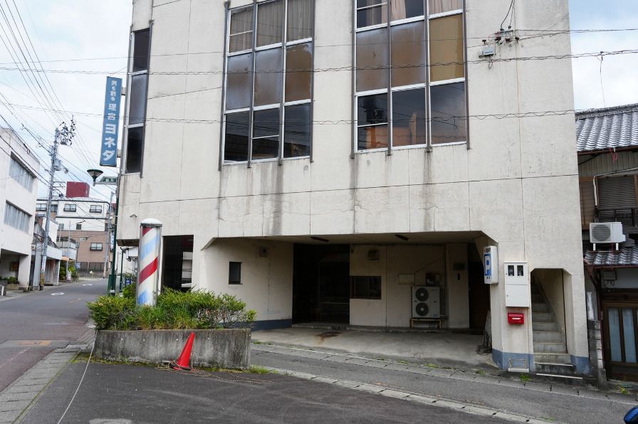 The building today: a white five-story building
          with an old barbershop entrance
